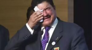 B.R. Shetty standing before the Abu Dhabi skyline at sunset, half illuminated by warm golden light and half in shadow, symbolizing the rise and fall of his business empire.