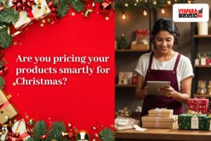 A smiling Sri Lankan small business owner stands at a festive shop counter, using a tablet while arranging neatly wrapped Christmas gift boxes with price tags. The left side of the image features a bright red background decorated with Christmas ornaments, pine leaves, and wrapped gifts, displaying the text “Are you pricing your products smartly for Christmas?” The Vyapara.lk logo appears in the top right corner.