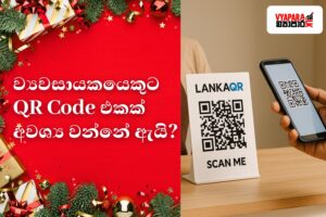 **“A Christmas-themed Sri Lankan business graphic featuring a red festive background with gifts and pine decorations on the left, displaying Sinhala text asking why entrepreneurs need a QR Code. On the right, a LankaQR stand is shown on a counter while a customer scans it with a smartphone, with the Vyapara.lk logo in the top corner.”**
