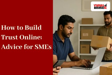 Trust Lanka | Three Sri Lankan small business workers in a modern workshop. A woman in a denim shirt is using her smartphone, a man in a navy polo shirt is working on a laptop, and another man in a brown shirt is carrying a cardboard box. A black delivery helmet and a sealed package are placed on the table, with more boxes stacked on shelves in the background.