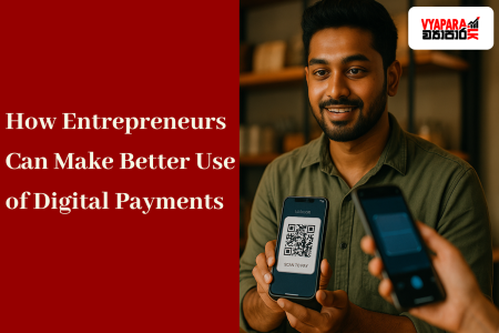 digital | A young Sri Lankan entrepreneur smiles while showing a smartphone with a QR code for payment inside a modern shop, as a customer scans it using another phone. The image has a red banner on the left reading “Better Use of Digital Payments” and the Vyapara.lk logo in the top right corner.