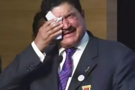 B.R. Shetty standing before the Abu Dhabi skyline at sunset, half illuminated by warm golden light and half in shadow, symbolizing the rise and fall of his business empire.