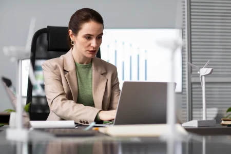 grow | Woman working on a laptop at a modern office desk with wind energy models.