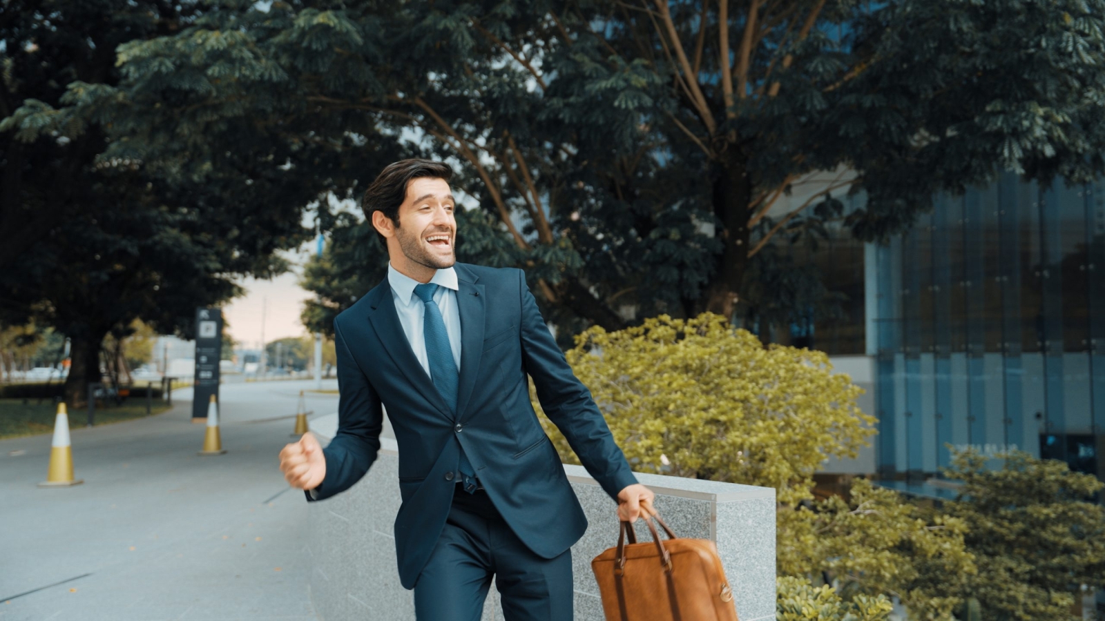 Smart business man walking along the road while holding bag at park. Professional project manager smiling while traveling in lively mood. Happy investor getting a promotion. Business dance Exultant.