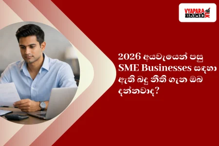 Business | Handsome fair-skinned Sri Lankan SME business owner reviewing financial documents at a modern desk, working on a laptop in a professional office setting.